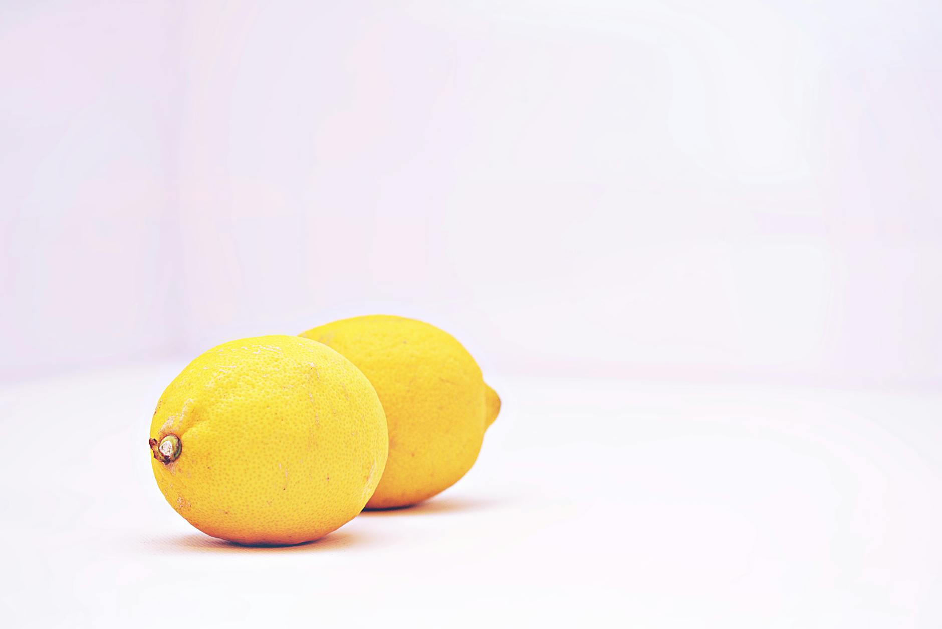 Two bright lemons on a white background, symbolizing freshness and self-care