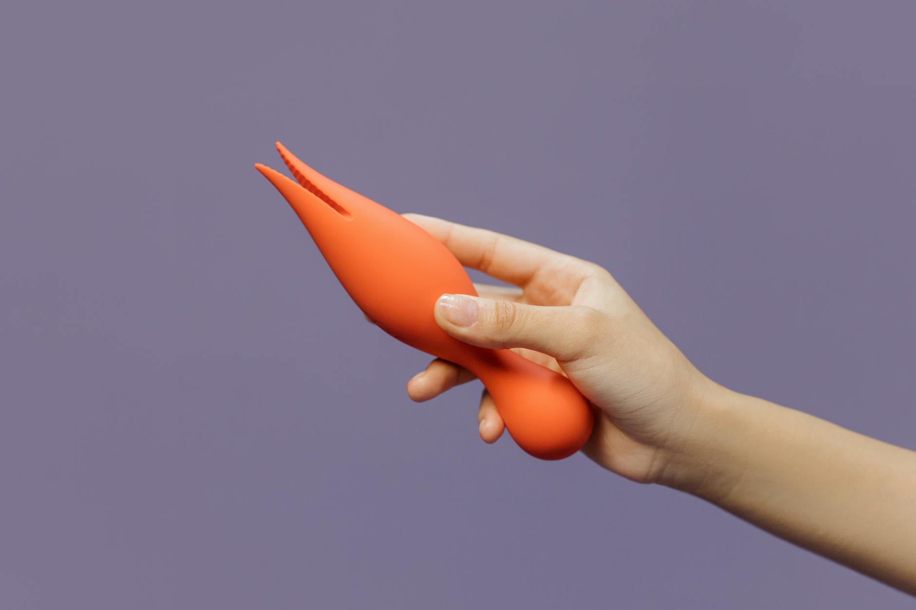 A close-up of a hand holding a lemon vibrator against a minimalistic purple backdrop, showcasing modern sensuality