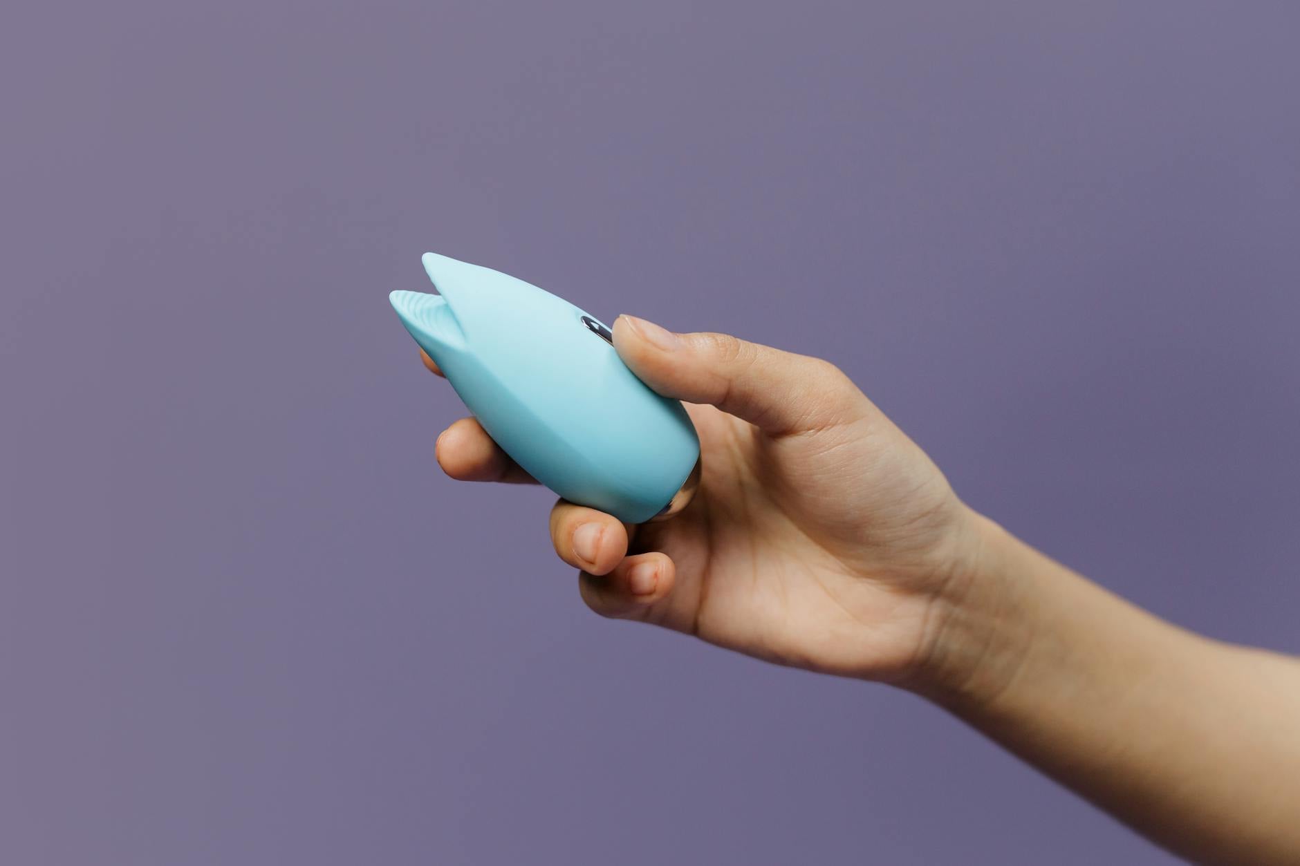 A hand holding a fresh lemon against a bright yellow background, symbolizing the citrusy approach to pleasure during menopause