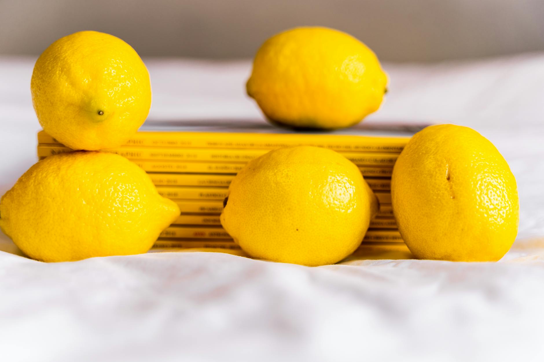 Fresh lemons stacked with books on white tablecloth, symbolizing mindful pleasure and patience